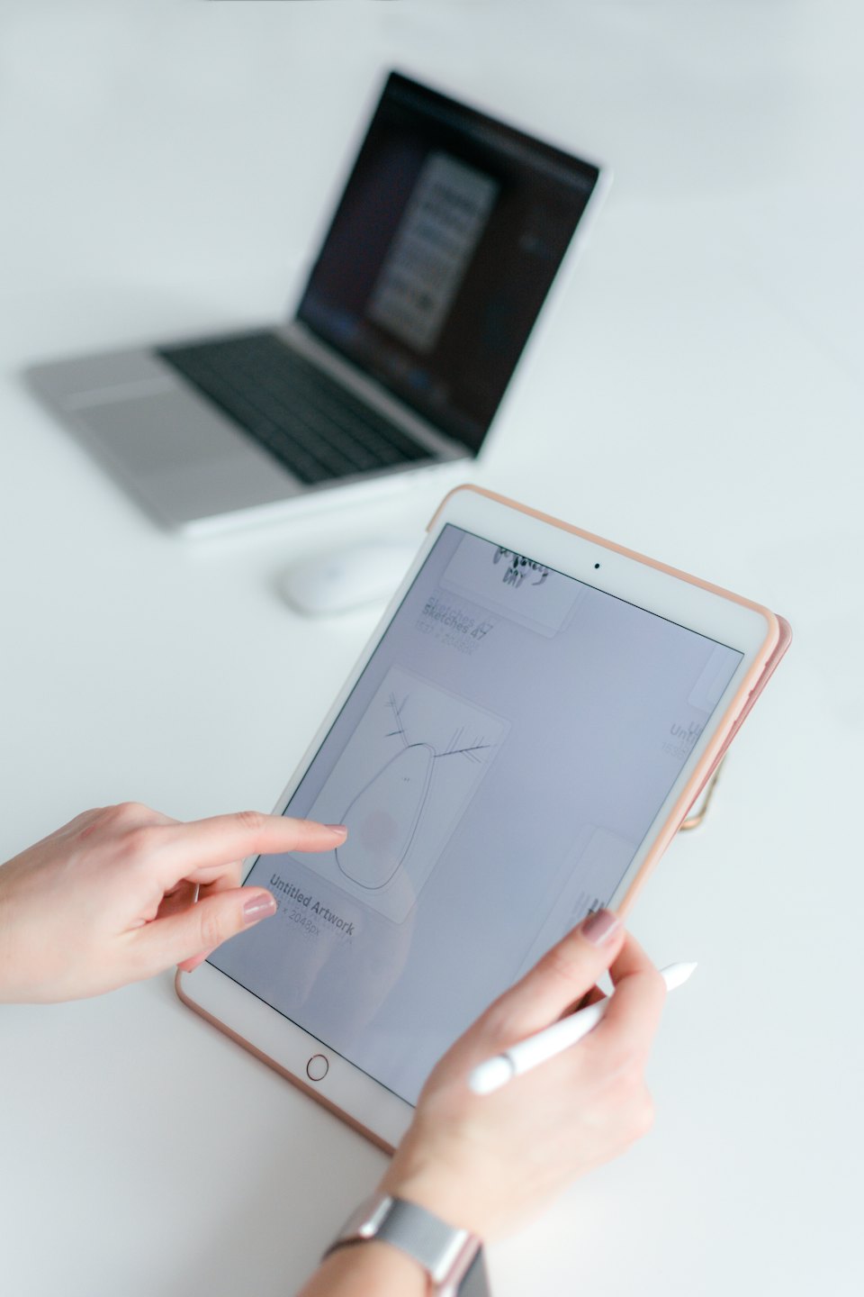 Hände, die einen Tablet-PC mit Stift auf einem weißen Schreibtisch bedienen.