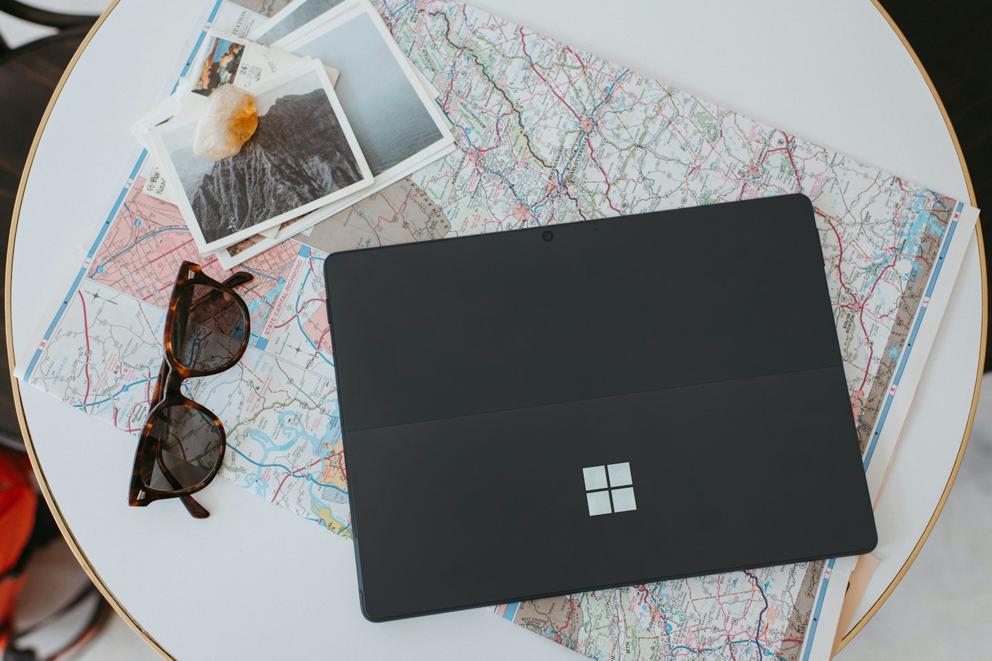 Laptop und Reiseutensilien auf einer Landkarte ausgebreitet zur Reiseplanung.
